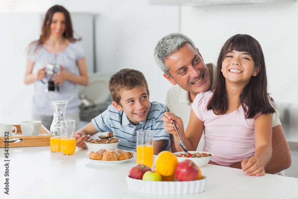 Smiling family eating breakfast in kitchen together Smiling family eating breakfast in kitchen together