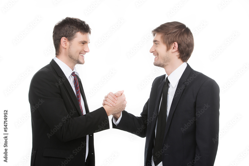 Business partners. Two cheerful business people shaking hands wh Business partners. Two cheerful business people shaking hands wh
