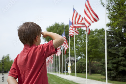 Boy salutes flags at Memorial Day display in a small town