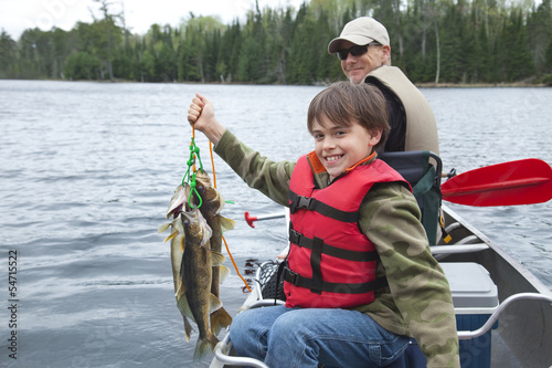 Young fisherman proudly holds stringer of walleyes photo