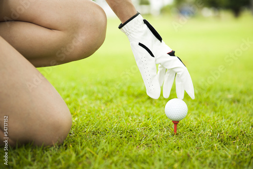 Lady placing golf ball on tee