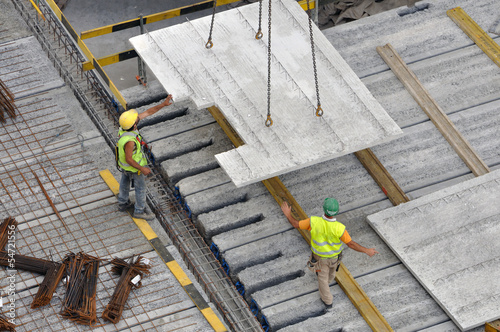 Ouvriers sur chantier reçoivent la plaque en béton de la grue