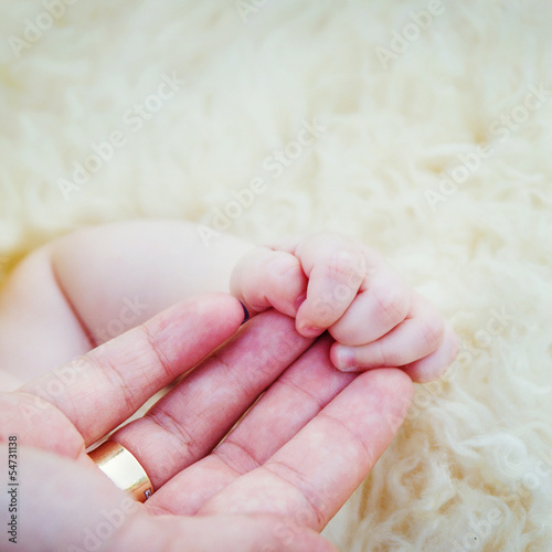 Newborn baby holding mothers finger