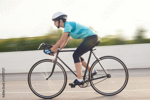 portrait of young female athlete racing on a bike. motion blurre