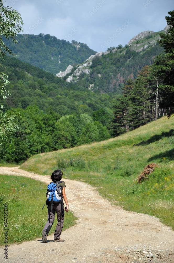 Winding dirt lane, mountain road with a trekking girl