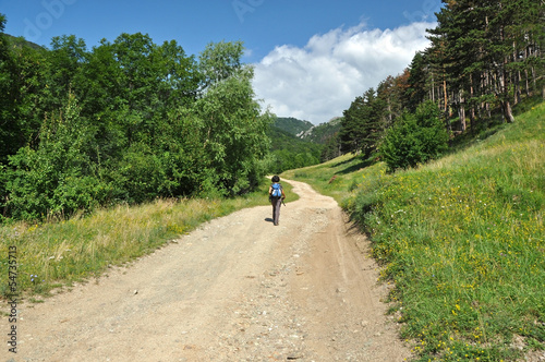 Winding dirt lane, mountain road with a trekking woman