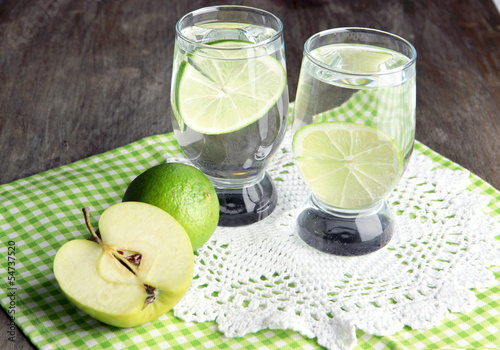 Glasses of cocktail with lime on napkin on dark wooden table