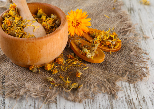 Fototapeta Naklejka Na Ścianę i Meble -  Fresh and dried calendula flowers in mortar on wooden