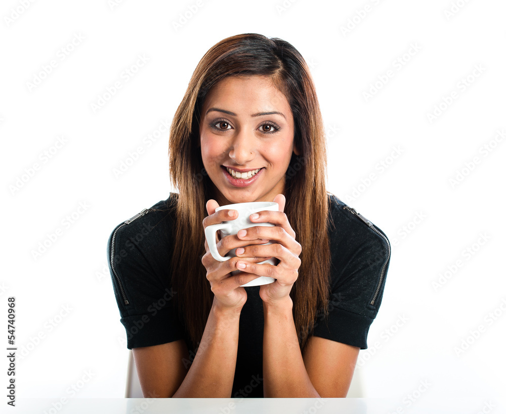 Attractive young asian indian woman enjoying a drink in a mug Attractive young asian indian woman enjoying a drink in a mug