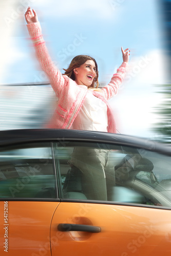 Woman having hun standing in car with arms raised