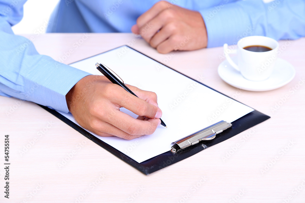 Businessman writing on document in office close-up