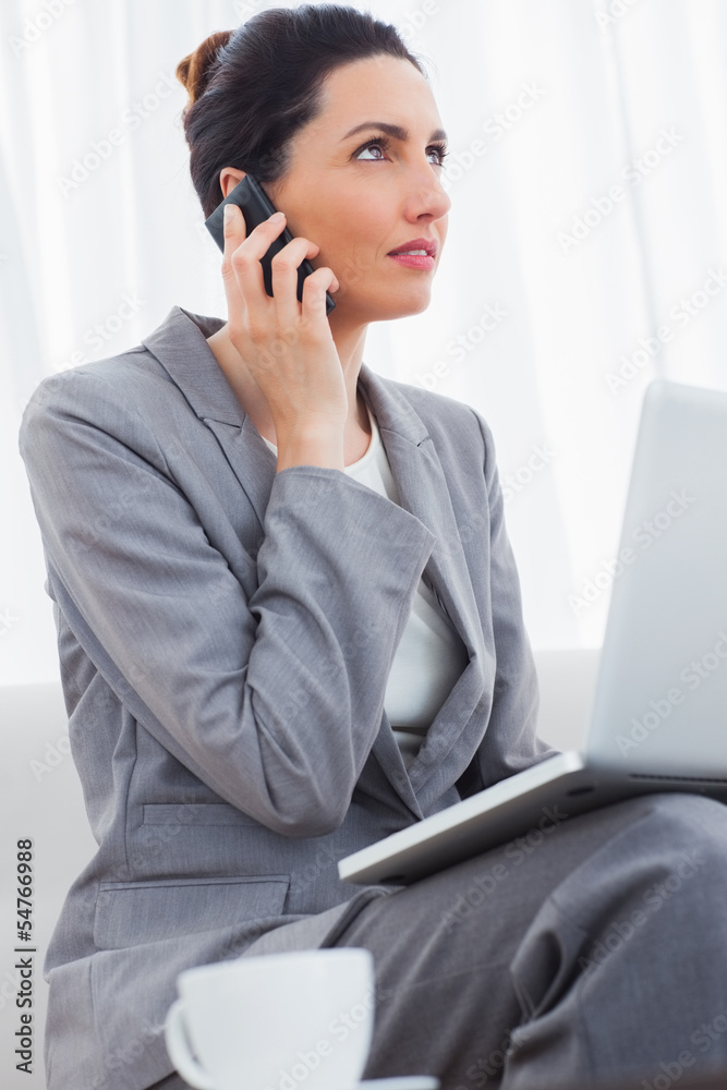 Businesswoman calling with her mobile phone and using laptop sit Businesswoman calling with her mobile phone and using laptop sit