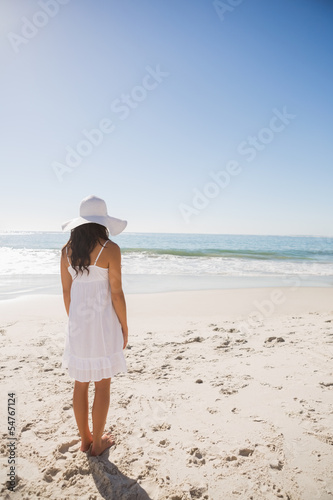 Brunette in white sunhat and dress looking at the ocean