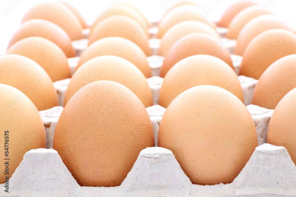 Raw eggs contained carton box focus near on white background. Raw eggs contained carton box focus near on white background.