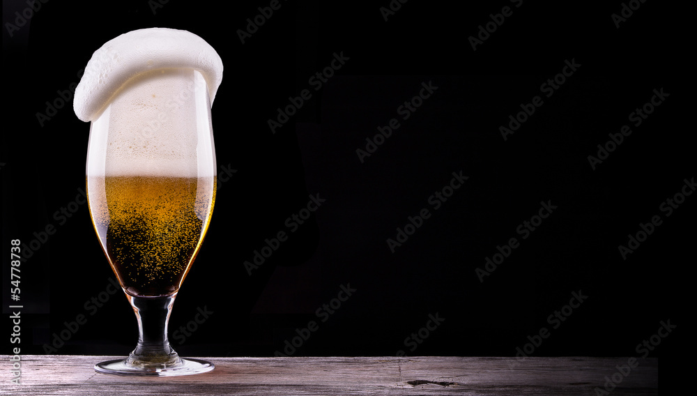 Frosty glass of light beer on black background