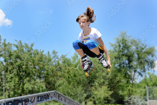 Teenage girl jumping in the air on rollerblades