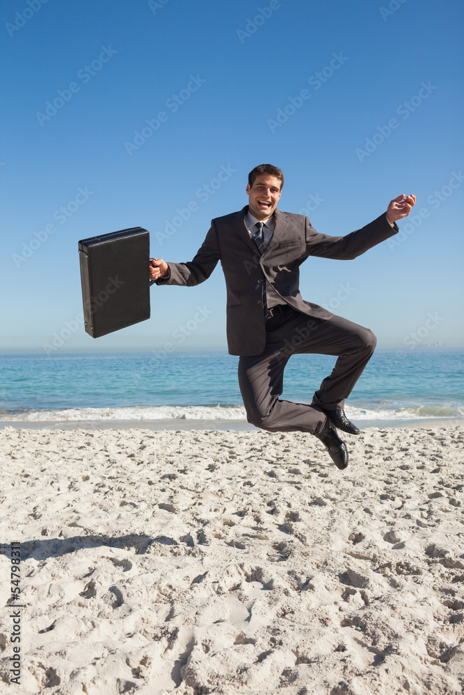 Cheerful businessman jumping on the beach Cheerful businessman jumping on the beach