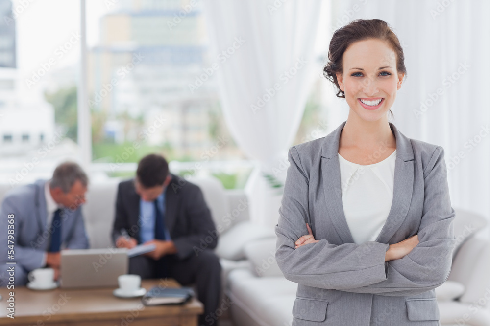 Cheerful businesswoman posing while her colleagues are working Cheerful businesswoman posing while her colleagues are working