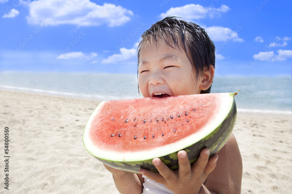 夏の海でスイカを食べる子供
