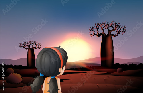 A young girl watching the sunset at the desert
