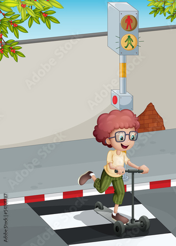 A boy with a scooter crossing the pedestrian lane