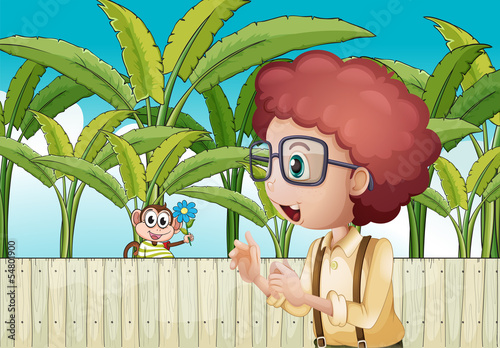 A boy and a monkey with a flower near the wooden fence
