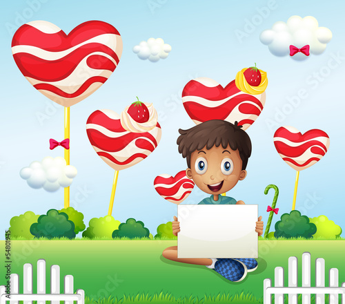 A smiling boy holding an empty signage at the candyland
