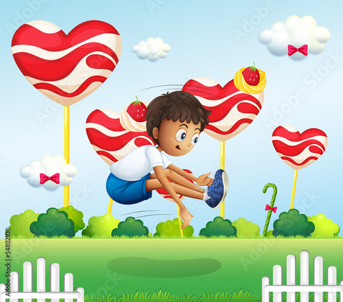 A boy jumping in the field with giant lollipops