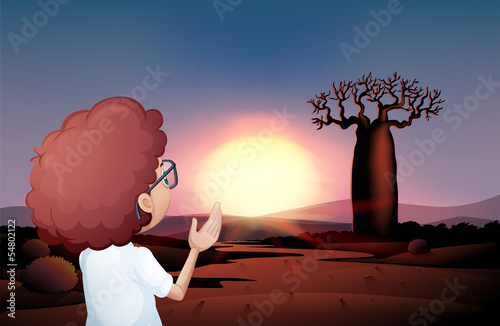 A curly boy watching the sunset in the desert