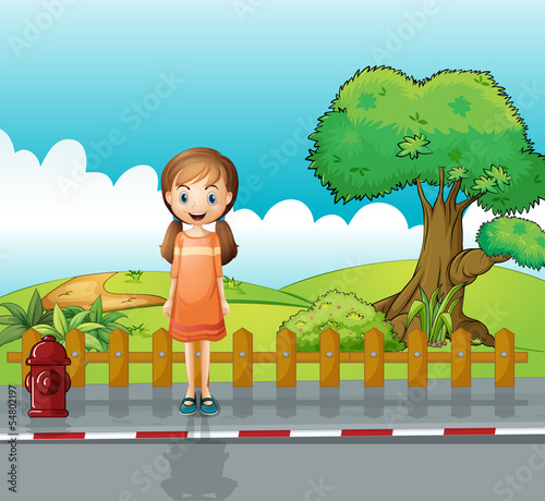 A small girl standing near the wooden fence