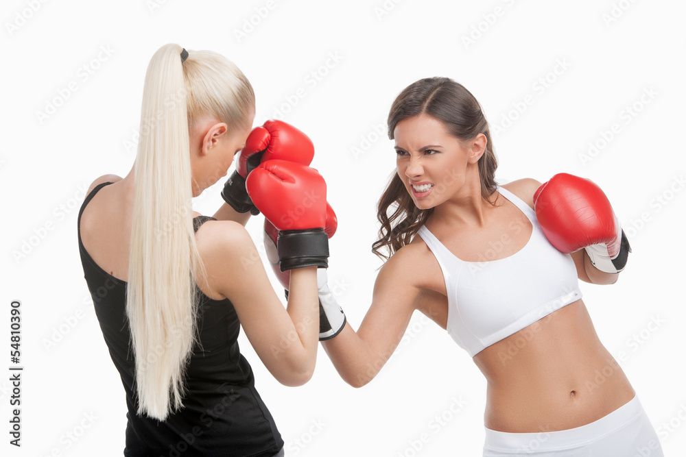 Women boxing. Two young confident women boxing while isolated on