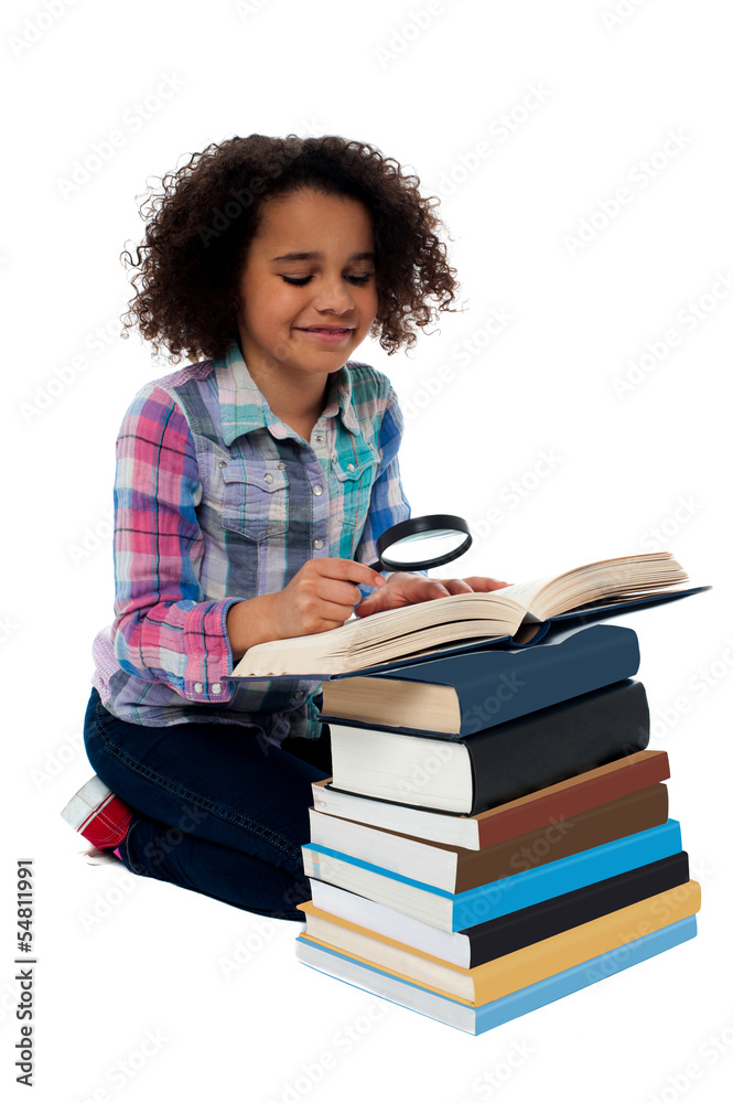 Cute kid reading book with magnifying glass Cute kid reading book with magnifying glass