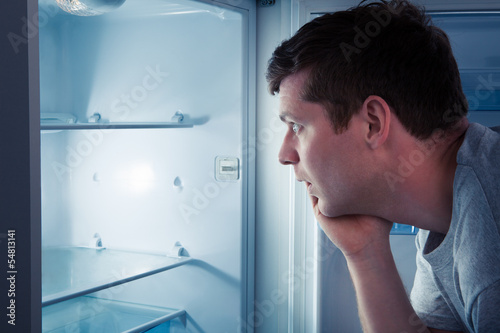 Hungry man looking in refrigerator photo