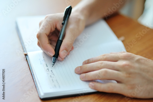 male hand writing on a notebook