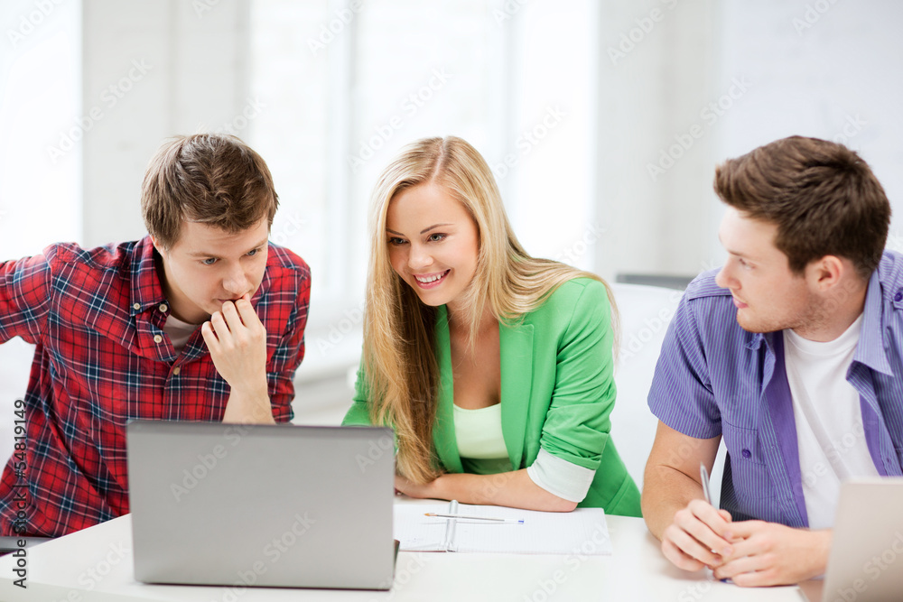 smiling students looking at laptop at school smiling students looking at laptop at school
