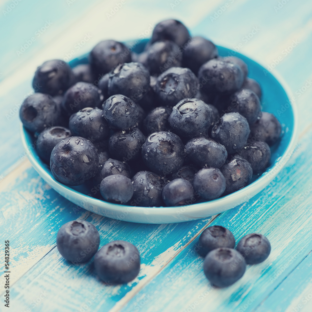 Saucer with ripe blueberries on wooden boards, close-up Saucer with ripe blueberries on wooden boards, close-up