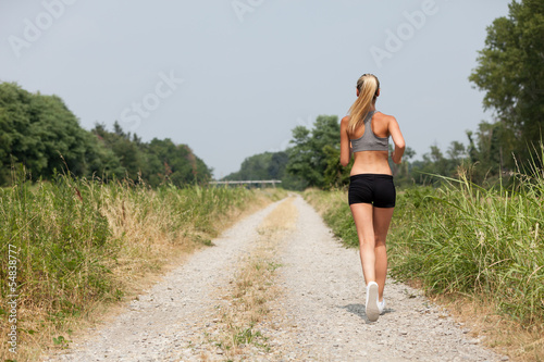 Beautiful blonde woman running along the riverside