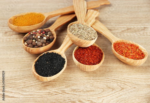 Assortment of spices in wooden spoons on wooden background