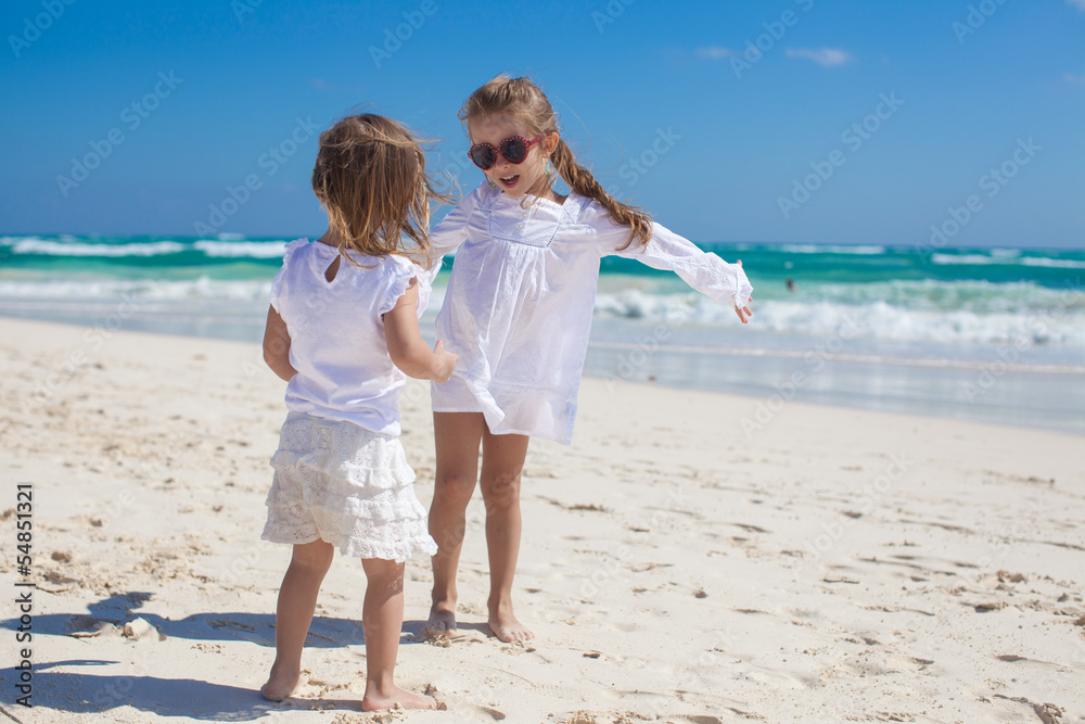 Two little sisters in white clothes have fun at tropical beach Two little sisters in white clothes have fun at tropical beach