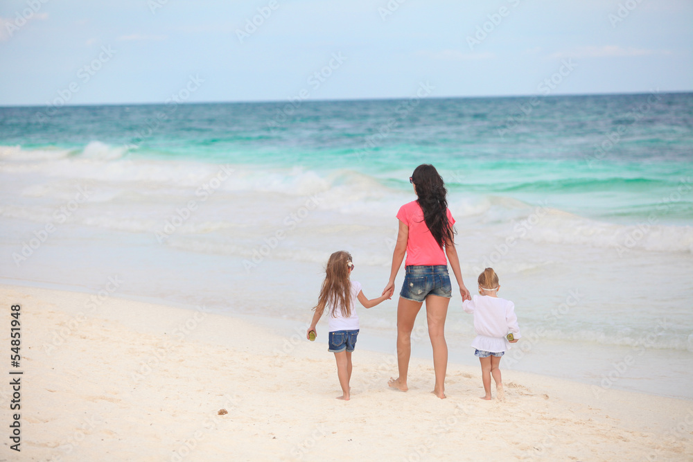 Back view of young mother and her cute daughters walking along