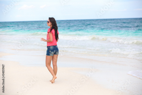 Back view of beautiful young woman standing in the water at