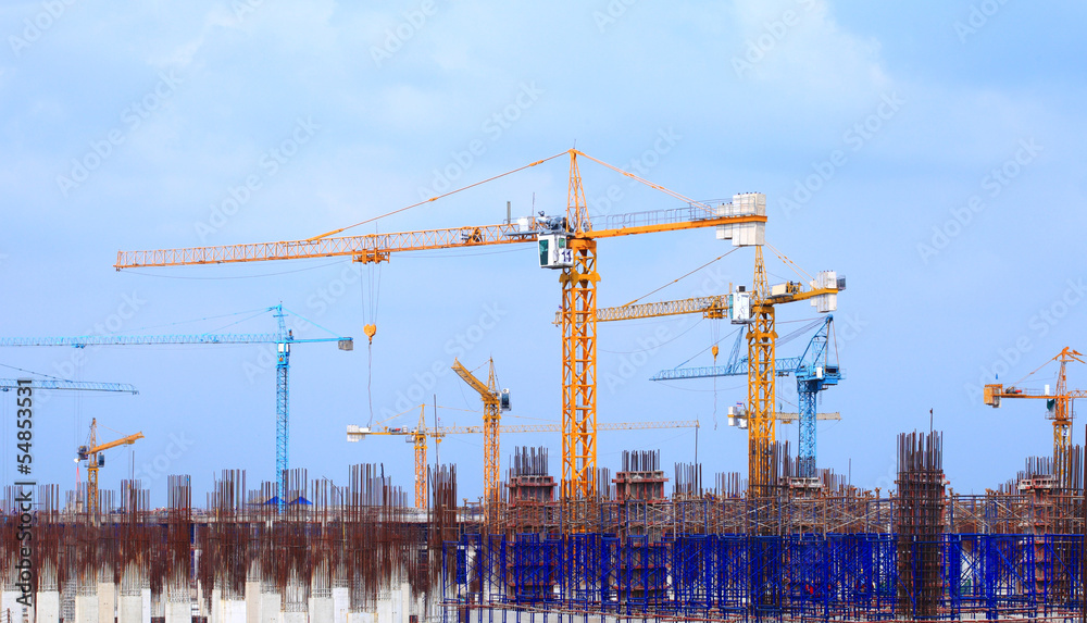 Construction site with multiple cranes on a blue background.