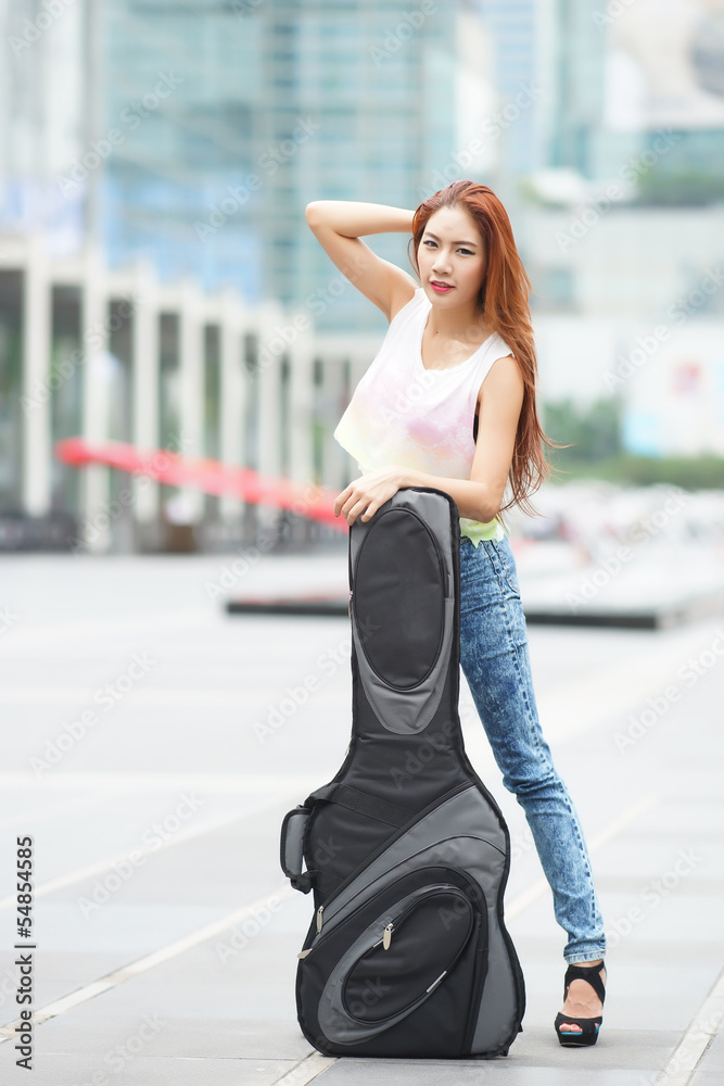 Young beautiful woman posing outdoor with her guitar gig bag Young beautiful woman posing outdoor with her guitar gig bag