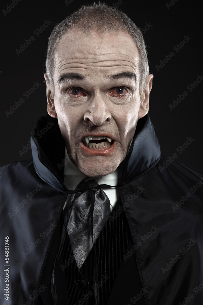 Dracula with black cape showing his scary teeth. Vamp fangs. Stu