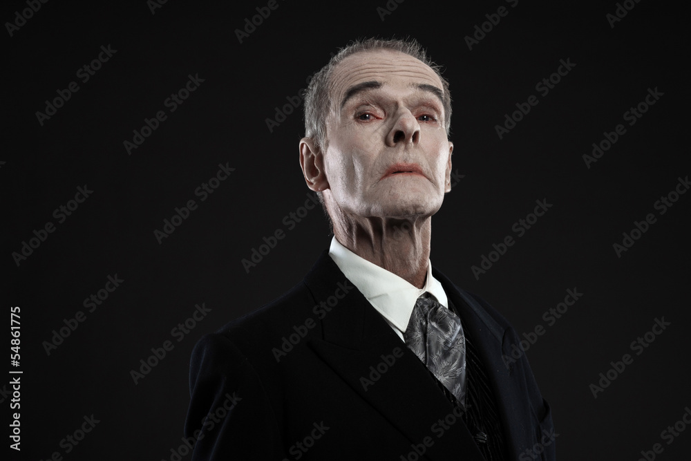 Fototapeta premium Scary count dracula in black suit. Pale head. Studio shot agains