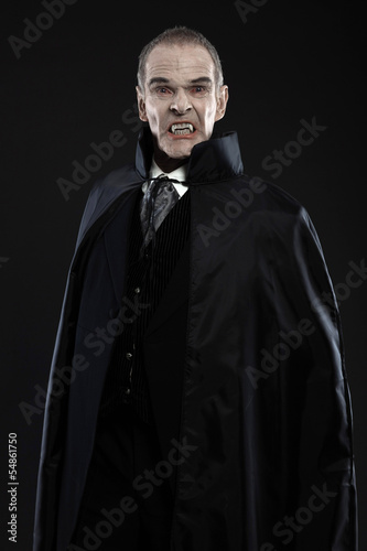 Dracula with black cape showing his scary teeth. Vamp fangs. Stu