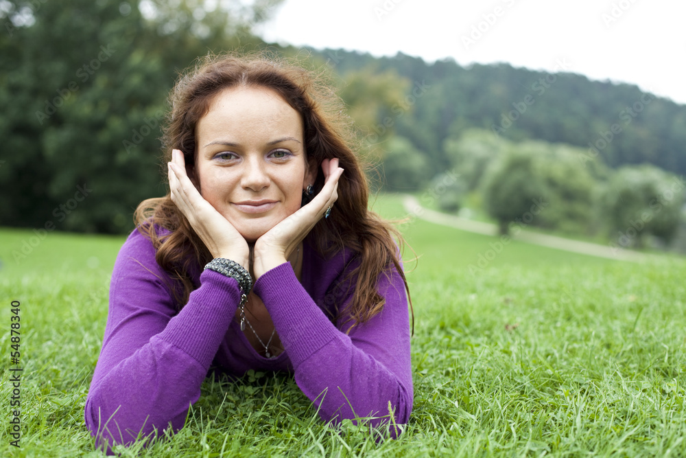Portrait of young woman lying on a green lawn Portrait of young woman lying on a green lawn
