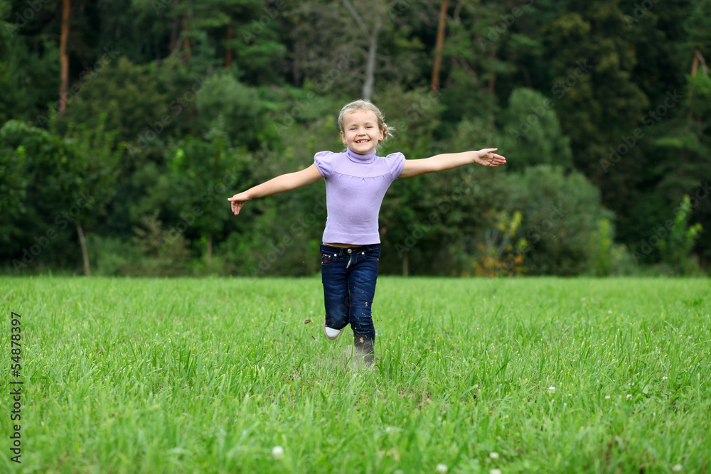 Little girl running on the meadow in summer day