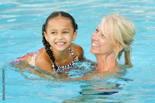 Mother and mixed race girl playing in pool during summer