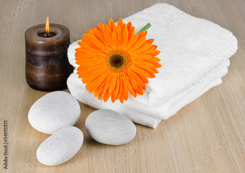 Spa decoration with candle, orange Gerbera daisy and spa stones